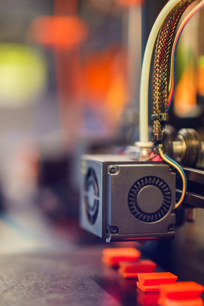 Detailed close-up of a 3D printer extruding red plastic during operation.